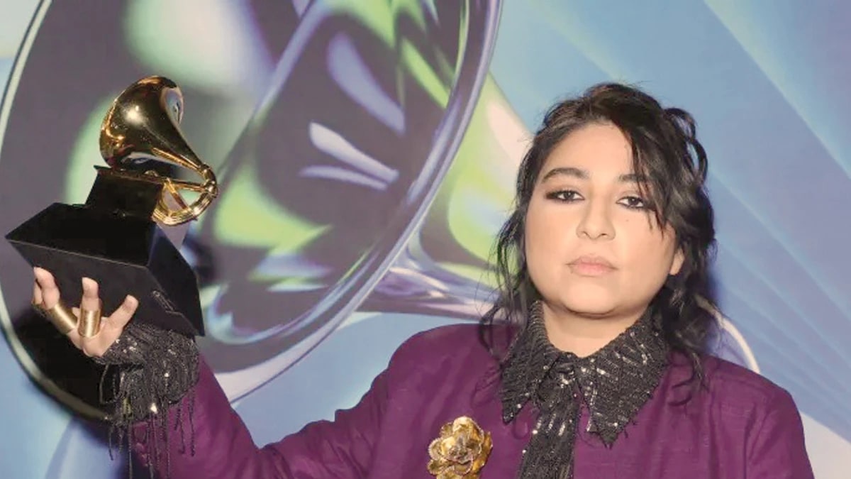 Arooj Aftab in a purple outfit holding up her Grammy award