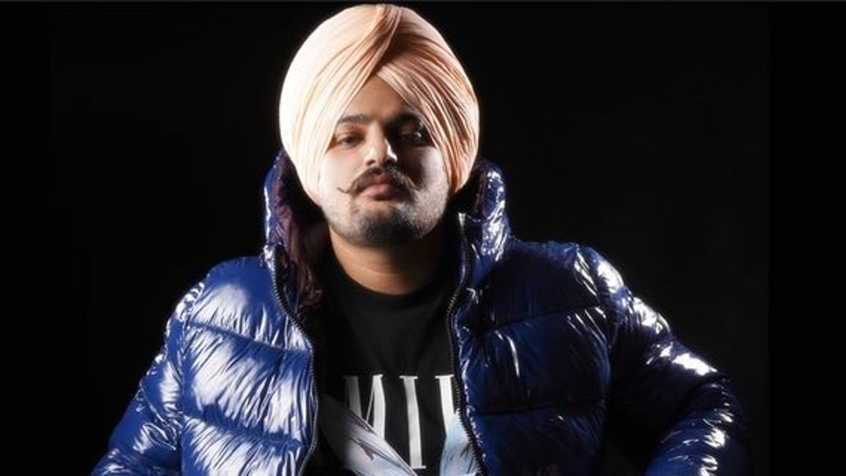 Sidhu Moose Wala in a blue puffer jacket against a black background